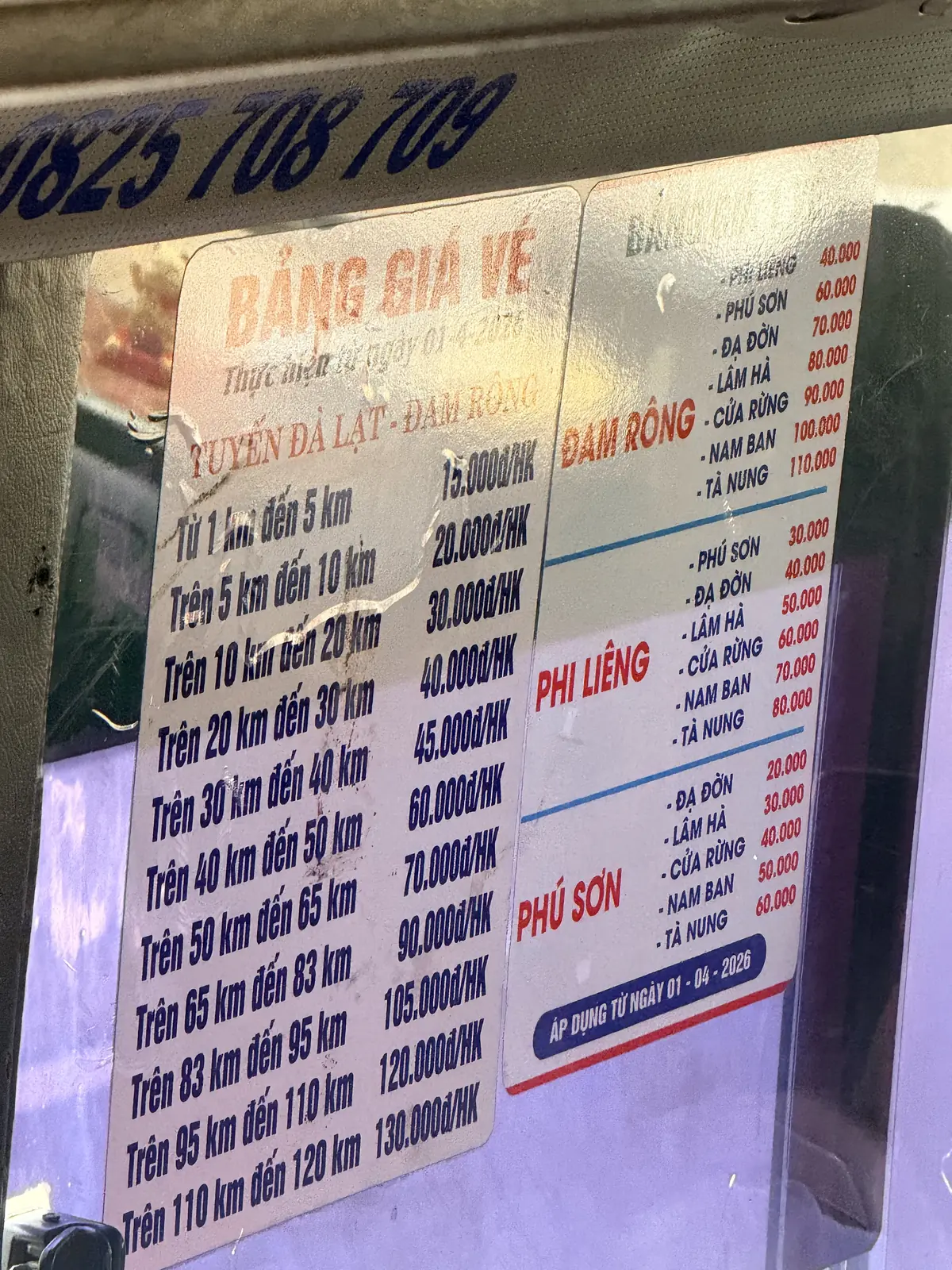 Bảng giá vé xe khách tuyến Đà Lạt – Đam Rông dán trên kính xe, có bậc giá theo ki-lô-mét và giá tới Nam Ban