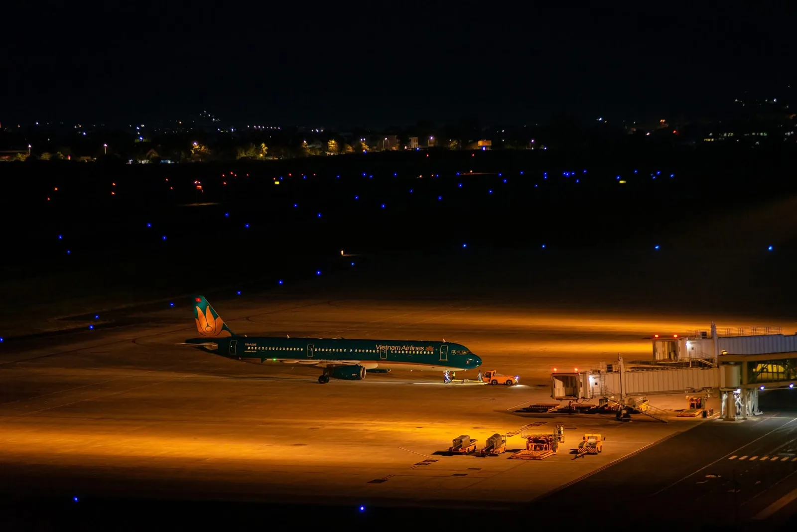 Máy bay Vietnam Airlines đậu ở sân đỗ Liên Khương ban đêm, cạnh ống lồng nhà ga