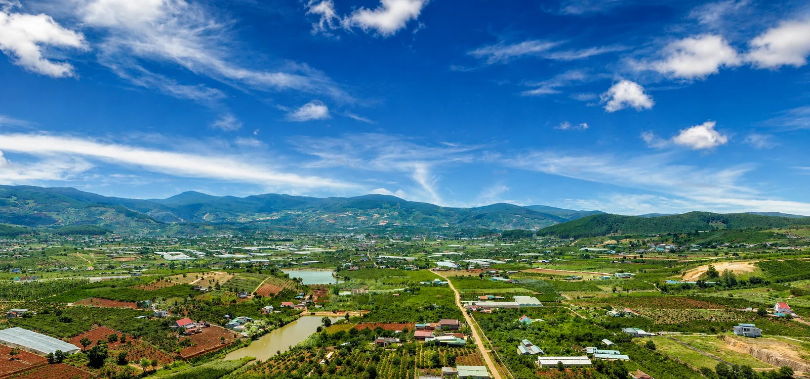 Toàn cảnh Nam Ban (Lâm Hà, Lâm Đồng) nhìn từ trên cao — thung lũng ruộng vườn, ao hồ, thị trấn và dãy núi cao nguyên gần Đà Lạt